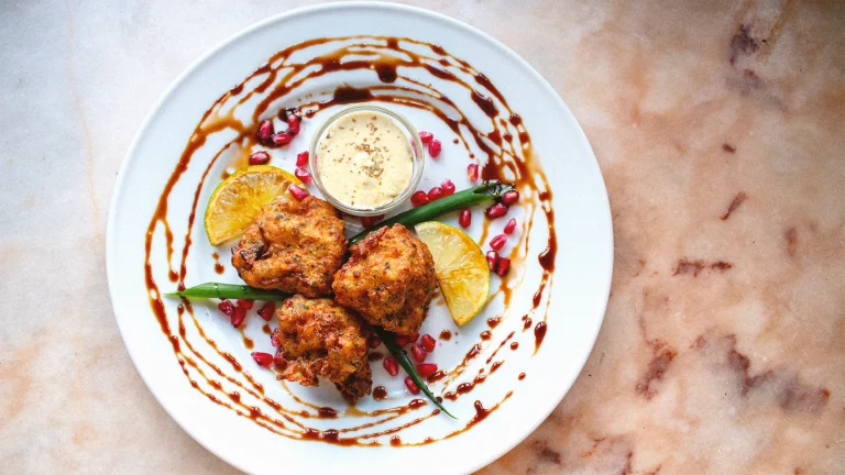 Fried appetizer with dipping sauce and pomegranate