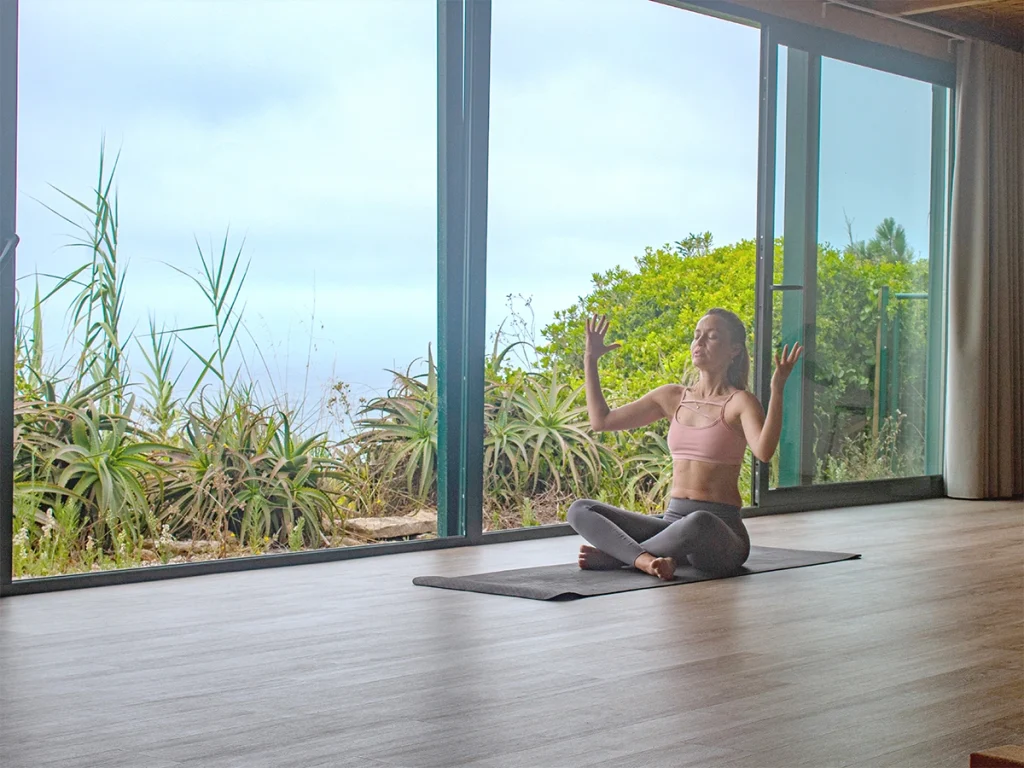 Woman doing yoga in front of large windows