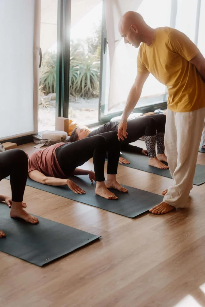People practicing yoga on mats with instructor guidance.
