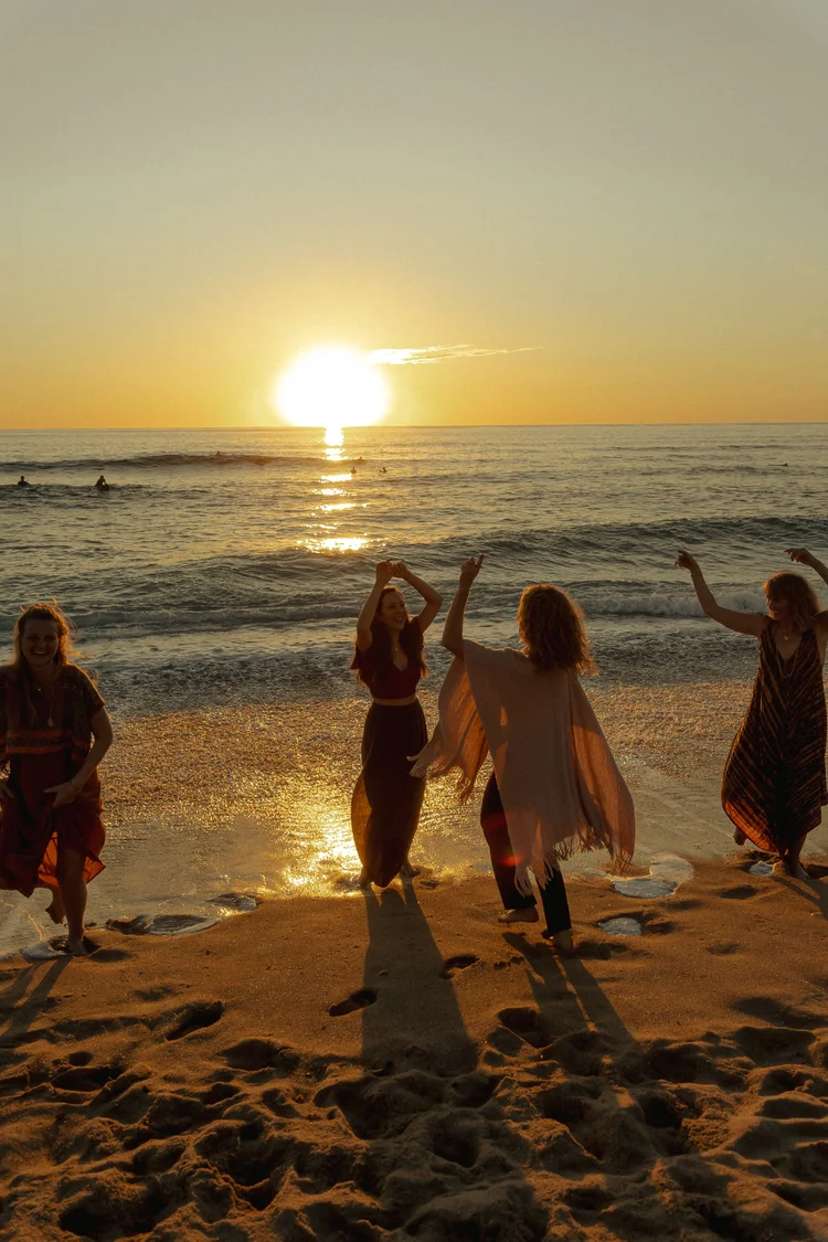 Women dancing on beach at sunset, Blossom Rose by Julie Pieper.